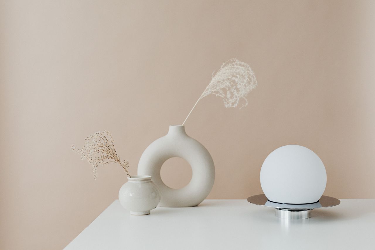 Minimalist arrangement of decorative vases and a modern lamp on a table.